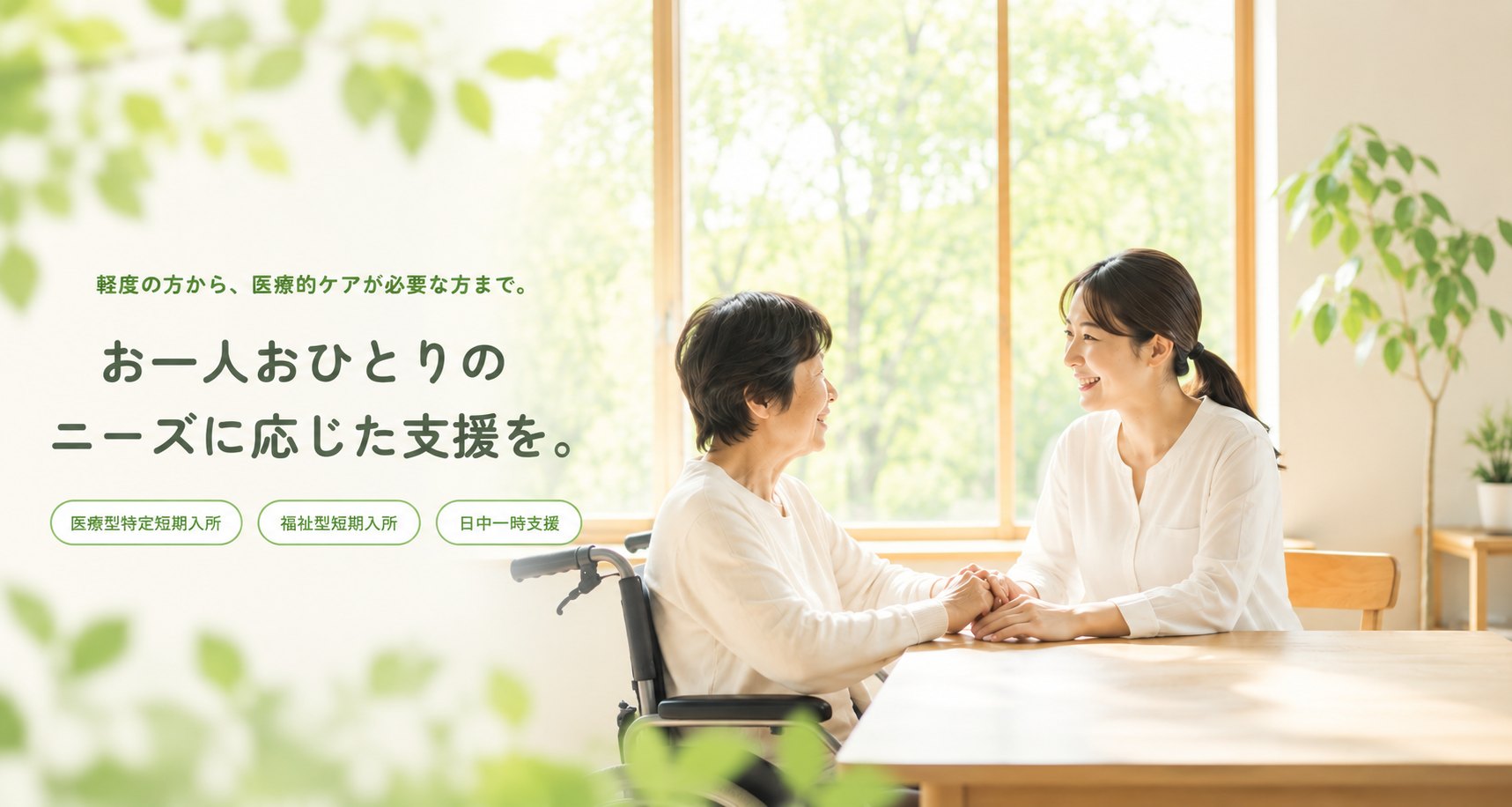 車椅子の利用者さんと、やさしく手を取り合うスタッフ。窓の外には新緑が広がる、ほっとステイ なずなの一場面